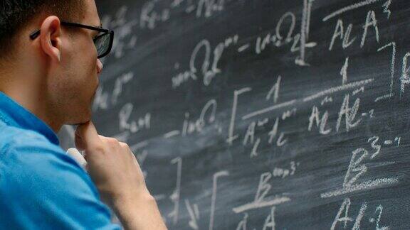 杰出的年轻数学家在黑板上写下复杂的数学方程公式
