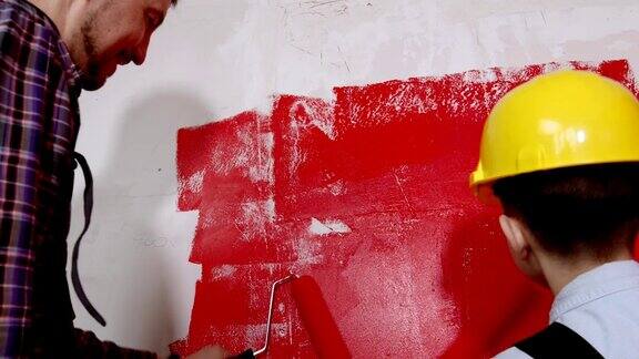 快乐的家庭装修公寓小男孩和他的父亲把墙漆成红色