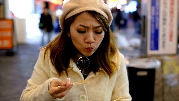 4K慢镜头:日本女子在道顿堀购物街夜市吃热章鱼烧