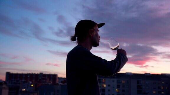 年轻人喝着酒看着城市的夕阳