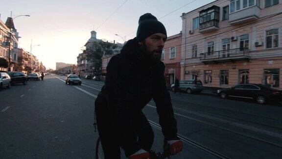 骑自行车的人骑固定齿轮运动自行车在阳光明媚的一天在一个城市日落
