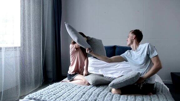 一对有趣的夫妇在床上用枕头打架