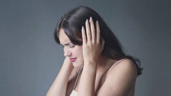 年轻的黑发女子闭上耳朵眼睛遭受噪音或声音的伤害