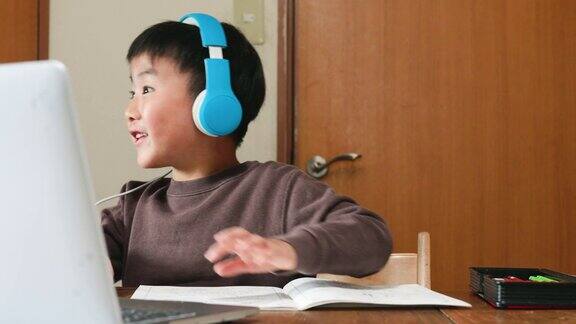戴着耳机的男孩正在用笔记本电脑上电子学习课程