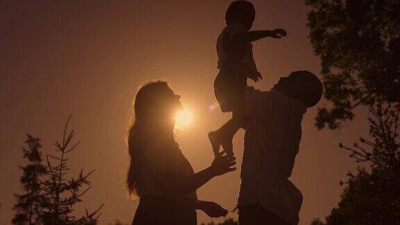 完整的家庭在日落爸爸妈妈和儿子的剪影一家人幸福在一起