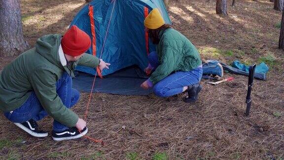 年轻的成年夫妇在森林里搭帐篷露营