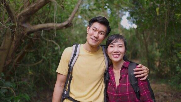 年轻的亚洲男人和女人的朋友一起在森林里旅行的肖像情侣们在大自然中感到清新和放松站在一起拥抱然后微笑着看着镜头