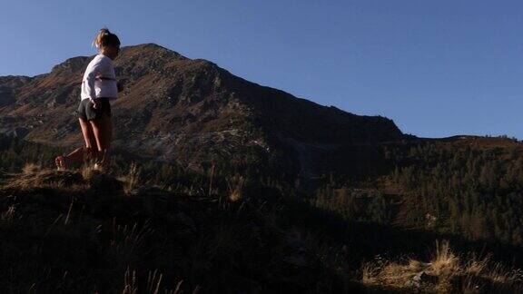 年轻女子沿着马特洪峰远处的山坡奔跑