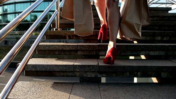 优雅的腿女人拿着购物袋在楼梯上