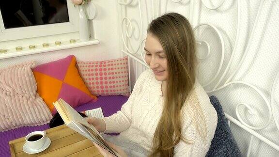 年轻漂亮的女孩一边看书一边享受早餐