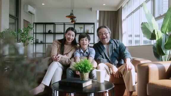 幸福快乐的亚洲家庭父母和儿子儿子一起看电视在客厅的沙发上度过假期的周末时间家庭和家庭
