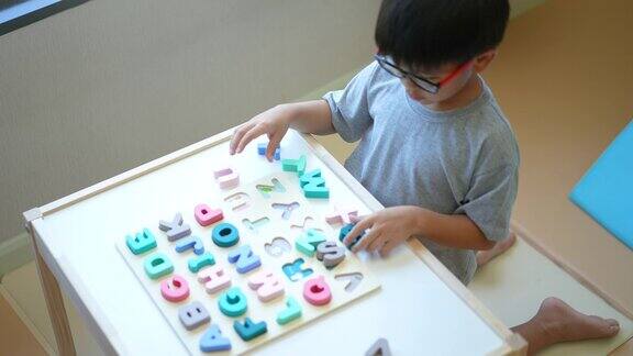 亚洲男孩学习英语字母玩具和字母表重返校园