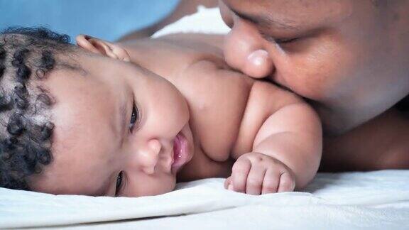 快乐的非洲父亲种族在卧室亲吻新生儿3个月而爸爸和宝宝在一起的时刻父亲节