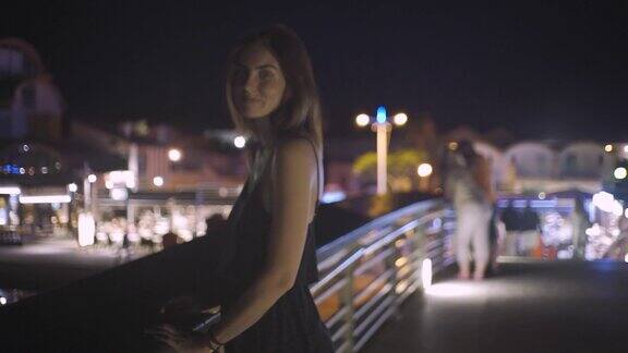 美丽的红发女人晚上在法国港口散步夜晚城市的背景是游艇