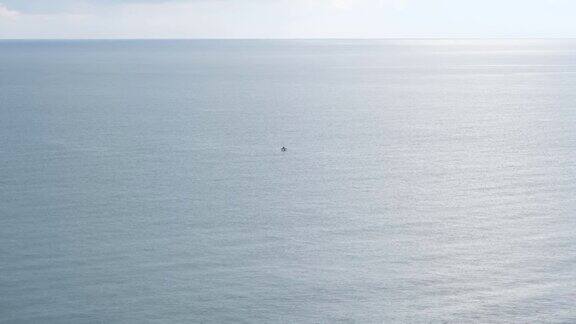 孤独的渔夫在平静的海水中捕鱼渔夫在一艘小船上远离海岸捕鱼
