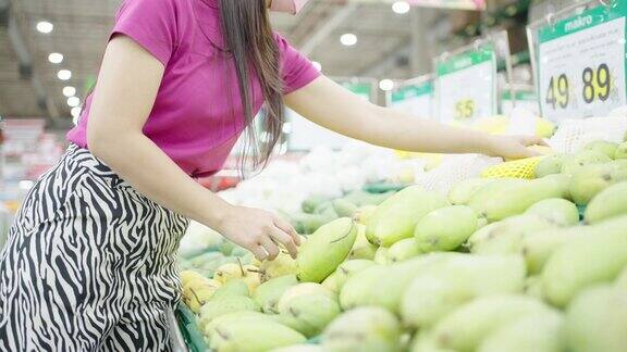新常态生活理念新冠肺炎疫情期间女性戴着医用口罩在超市购买新鲜食品蔬菜