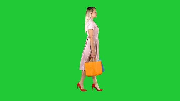 快乐漂亮的女孩抱着购物袋走在绿色屏幕上色度键