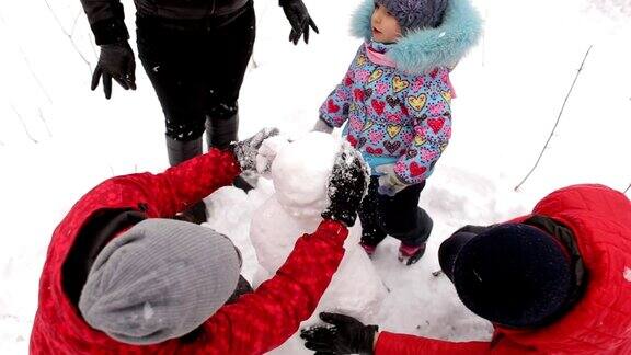 一家人带着孩子在公园里堆雪人