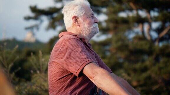 70多岁的老人坐在山顶上在大自然中做呼吸练习