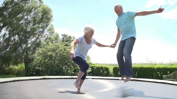 一对老年夫妇在蹦床上慢动作跳跃