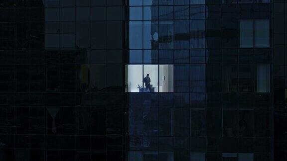 鸟瞰图镜头:从外面到办公大楼商人使用手机站在办公室窗户旁美丽的金融商业区摩天大楼的飞行镜头