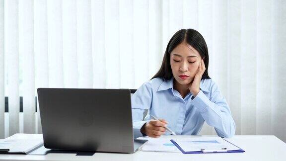 年轻的亚洲商务女性在办公室用笔记本电脑和智能手机努力工作的4k视频片段