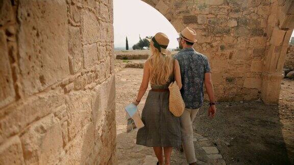 年轻的游客夫妇参观地中海岛屿上的古老的石头教堂