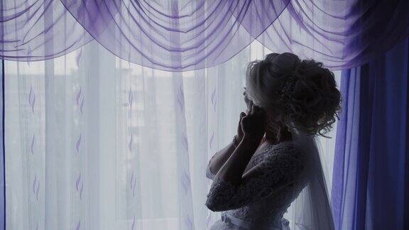 美丽的新娘在窗口关闭耳环