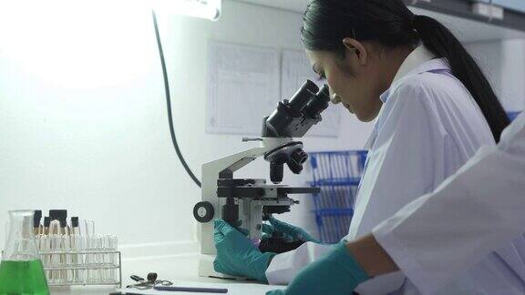 实验室里的研究人员可以是法医学团队、医学研究人员或大学学生男女科学家正在实验室里用显微镜和平板电脑工作