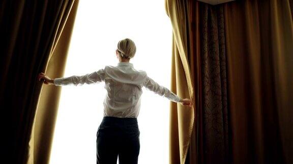 女商人早上拉开酒店房间的窗帘望向窗外