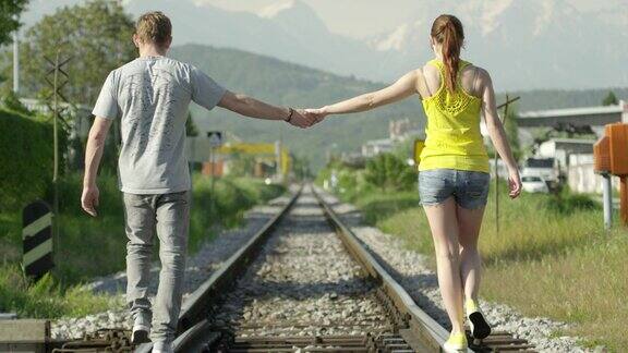 慢镜头:情侣手牵着手走在铁轨上