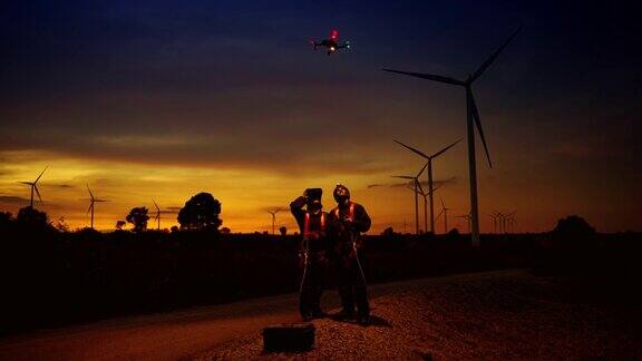 黄昏时分涡轮维修工程师利用无人机对风力涡轮机现场的维修点进行观察