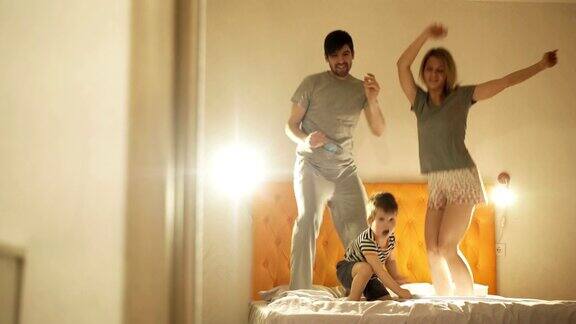 快乐的家庭和小儿子跳舞在晚上睡觉前在家里的床上玩