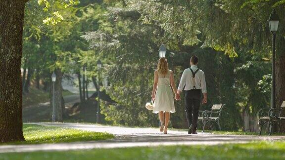 新婚夫妇手牵着手在公园里散步