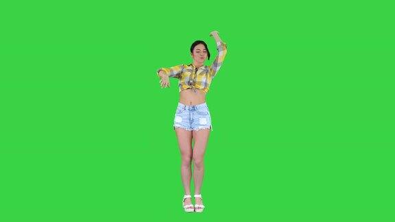 女孩穿着方形衬衫和牛仔裤短裤运动鞋在绿色屏幕上跳舞色彩之键