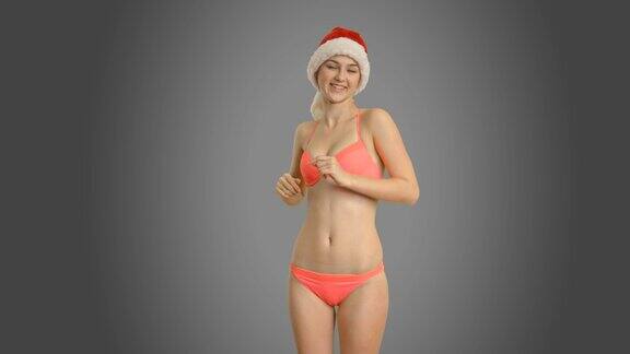 快乐的女孩穿着泳衣和帽子跳舞的圣诞老人