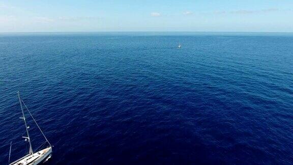 航拍:蓝色大海中的帆船在地平线上可以看到一艘帆船