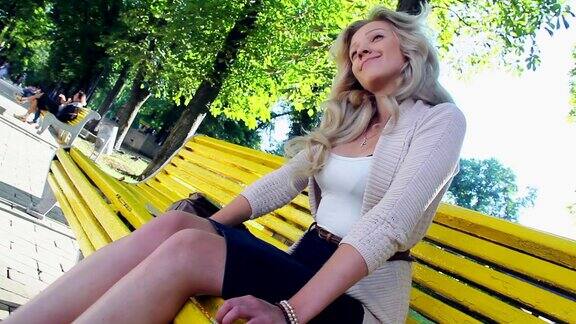 欣赏在公园长椅上微笑的年轻美丽的女性