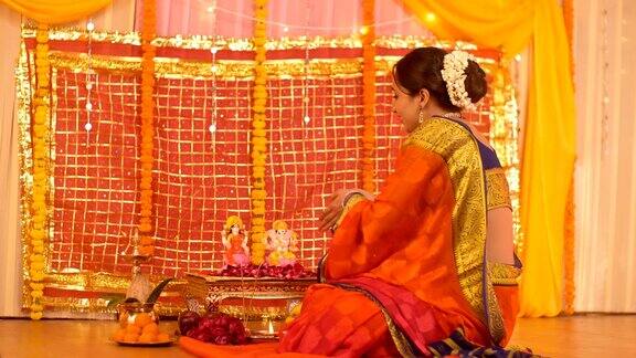 一名印度妇女面对着镜头在家向印度教主的神像献花