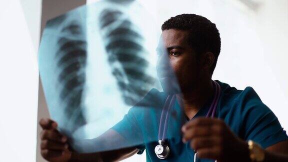 年轻的非洲裔美国男子医生穿着外科医生服研究胸部x光图像的特写