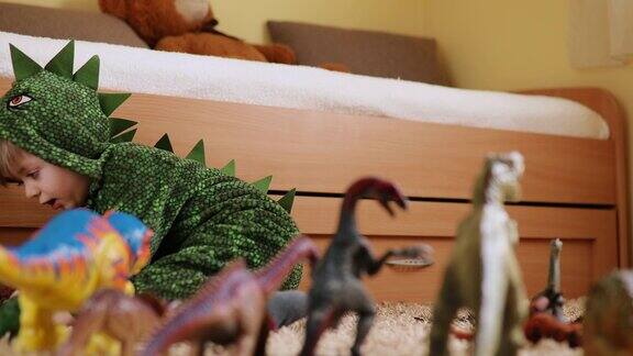 可爱的小男孩穿着恐龙服装和他的恐龙玩
