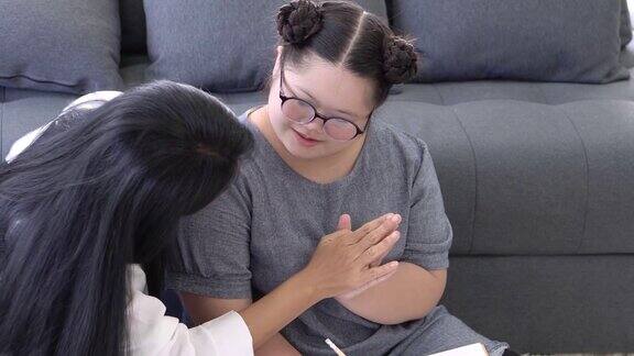 亚洲母亲和患有唐氏综合症的女儿在家里画家庭画