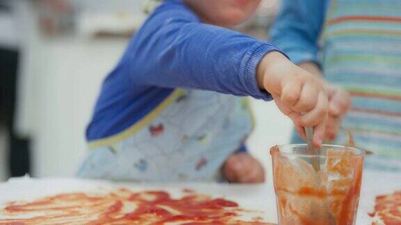 小男孩用勺子把番茄酱放在披萨上