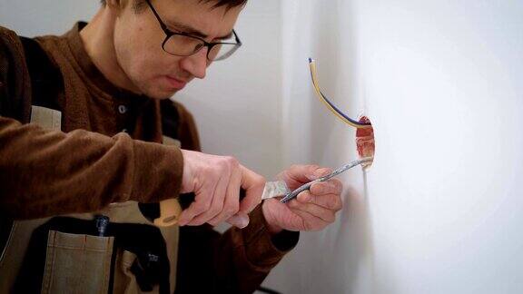 电线工人正在房间内用文具刀剥电线用于安装插座切割电缆护套