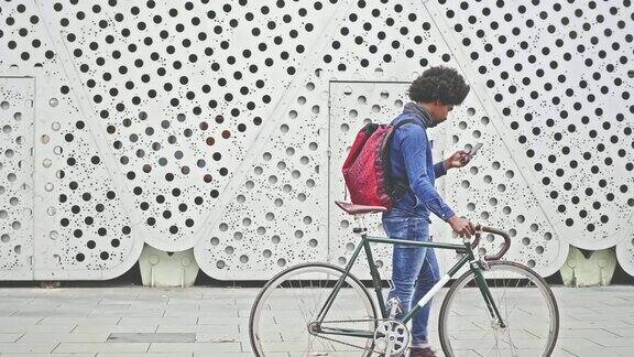 嬉皮士骑着自行车在大街上用手机走路的慢动作视频