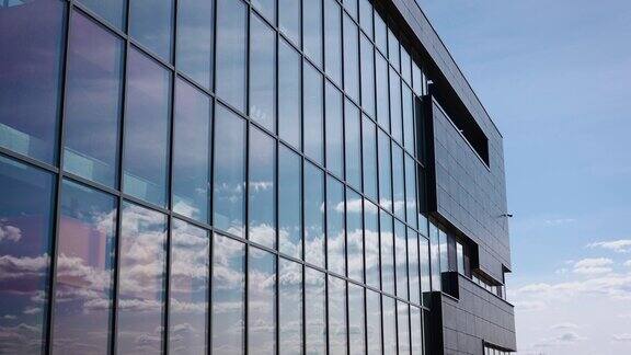 云和天空反射在办公楼外立面的玻璃窗上商业建筑风格的时尚和严谨