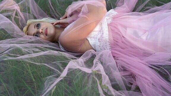 穿着粉红色衣服的漂亮年轻女子躺在草地上
