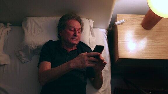 男人晚上在床上看手机俯视图老年人使用智能手机