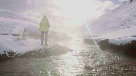 女士站在冰岛雪山上的温泉