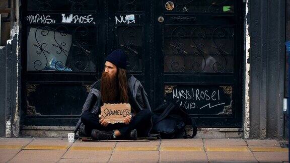 一个无家可归的人拿着“无耻”纸板在拥挤的街道上乞讨